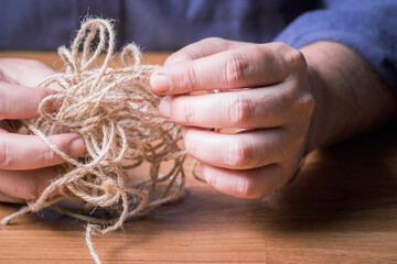 Closeup man try to fix the problem of tangled jute rope
