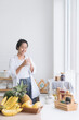 © Thirawatana - Asian woman making banana milk in the kitchen. Female drinking smoothie in the kitchen.