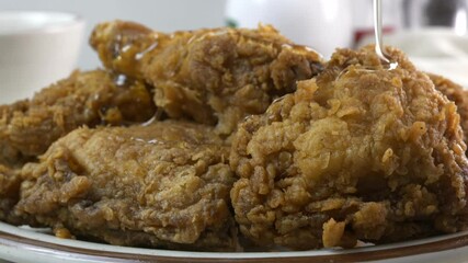 Wall Mural - Pouring honey onto breaded fried chicken close up slow motion