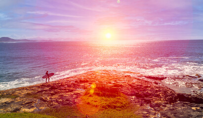 A magnificent sunrise greets a young surfer on his way out over the rock platform to catch his first ride of the day.