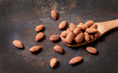 top view of almonds in wooden spoon on a beautiful dark vintage style old table. Almonds in a wooden bowl and put in a wooden spoon, the nuts are poured freely. , healthy food and vegetarian