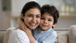 © fizkes - Happy young Indian mom hugging cute little smiling son with cheek touch, looking at camera. Grateful mother embracing kid tightly with love, affection, tenderness. Family, motherhood concept