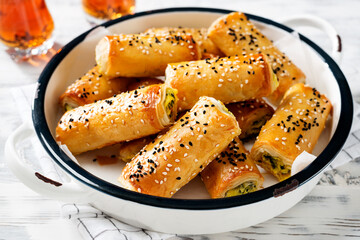 Wall Mural - Turkish borek rolls with spinach and cheese. A traditional Turkish pastry rulo borek with black and white sesame seeds. White  wooden background.