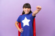 © luismolinero - Little kid isolated on purple background in superhero costume with proud gesture