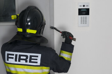 a firefighter tries to open the iron entrance door in the entrance, with a crowbar, close-up