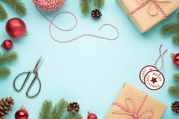 Wall Mural - Top view photo of pine twigs cones red christmas tree balls scissors spool of decorative rope merry christmas tags and two craft paper gift boxes on isolated pastel blue background with blank space