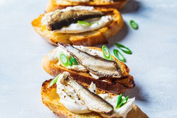 Wall Mural - Toast with cream cheese, sprats (sardine) and green onions. Simple homemade recipes concept.