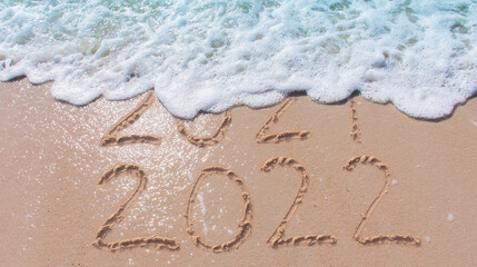 Wall Mural - message year 2021 replaced by 2022 written on beach sand background. good bye 2021 hello to 2022 hap