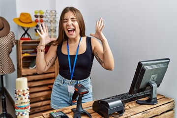 Poster - Young brunette woman holding banner with open text at retail shop celebrating mad and crazy for success with arms raised and closed eyes screaming excited. winner concept