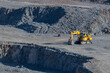 Yellow hydraulic excavator with crawler wheels in the mine with grey background
