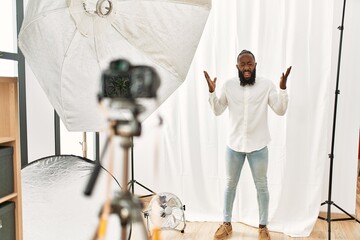 Sticker - African american man posing as model at photography studio celebrating mad and crazy for success with arms raised and closed eyes screaming excited. winner concept