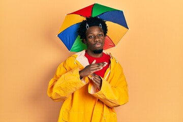 Sticker - Young african american man wearing yellow raincoat doing time out gesture with hands, frustrated and serious face