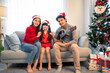 Portrait of Asian happy family wear Santa hat, sitting in living room. 