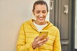 © Krakenimages.com - Young hispanic girl smiling happy using smartphone and earphones at the city.