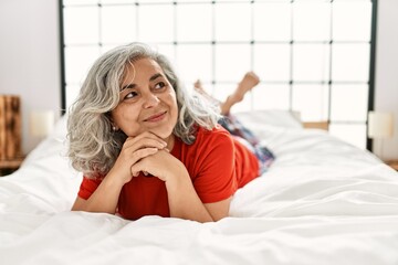 Sticker - Middle age grey-haired woman smiling happy lying on the bed at bedroom.