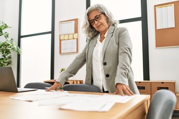 Poster - Middle age grey-haired businesswoman working at the office.