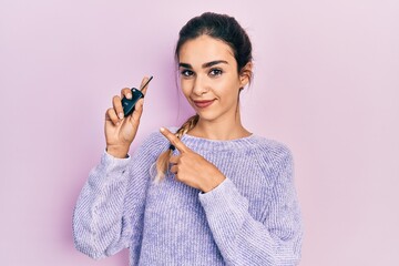 Wall Mural - Young hispanic girl holding key of new car smiling happy pointing with hand and finger