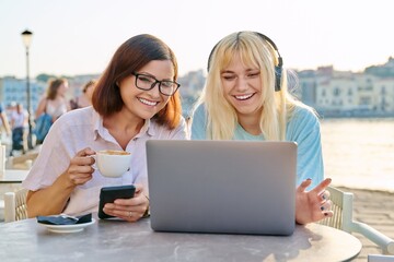 Poster - Mom and teenage daughter looking at laptop together, sitting in an outdoor cafe