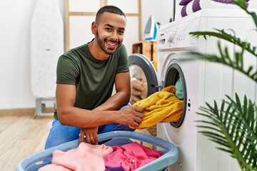 Canvas Print - Young hispanic man cleaning clothes using washing machine at laundry