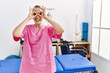 © Krakenimages.com - Young blonde woman working at pain recovery clinic doing ok gesture like binoculars sticking tongue out, eyes looking through fingers. crazy expression.