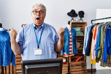 Sticker - Senior man with grey hair working as manager at retail boutique celebrating surprised and amazed for success with arms raised and open eyes. winner concept.