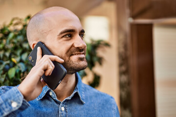 Poster - Young hispanic man smiling happy talking on the smartphone at the city.