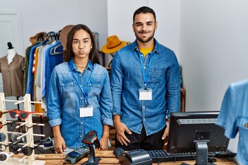 Canvas Print - Young interracial people working at retail boutique puffing cheeks with funny face. mouth inflated with air, crazy expression.