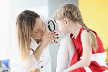 Wall Mural - Ophthalmologist conducts medical examination of girl eye through magnifying glass