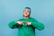 © bodnarphoto - Positive hipster girl with dyed hair shows a heart gesture to the camera those looking with a smile on her face.