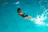 Fototapeta Do akwarium - unrecognizable kid swimming freestyle style training in swimmer pool with splashing water. selective focus
