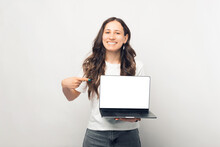 Cheerful Young Woman Pointing At Blank Screen On Laptop Over White Background.