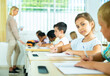 © JackF - Portrait of positive tween schoolgirl sitting on lesson in classroom, looking at camera with smile