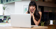 © PAPALAH - Latin businesswoman in the office, Co-working space, Happy and excited about the results. Staring at the laptop on the desk.