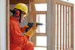 © DragonImages - Side view of concentrated builder with drill using self-tapping screw when working with wood