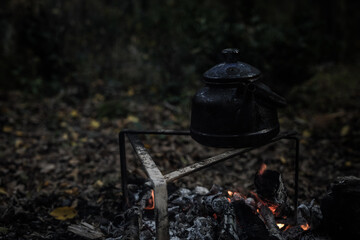 Wall Mural - With knife, water bottle and titanium mug near the fire outdoors. bushcraft, adventure, travel, tourism and camping concept.