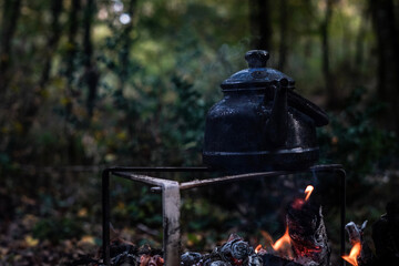 Wall Mural - With knife, water bottle and titanium mug near the fire outdoors. bushcraft, adventure, travel, tourism and camping concept.