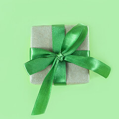 Wall Mural - The above view on the present packed in the craft paper with the green satin ribbon on the green background. Minimalism New Year or Christmas concept.