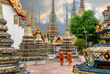 Fototapeta  - Two monks walking alongside stupas at the Wat Pho Temple in Bangkok