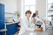 © Westend61 - Smiling researcher with microscope at desk