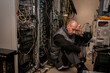 © Климов Максим - A frustrated technician sits in a server room. A man sits on the floor in a data center among many wires.