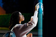 © Westend61 - Young woman touching kiosk screen at night