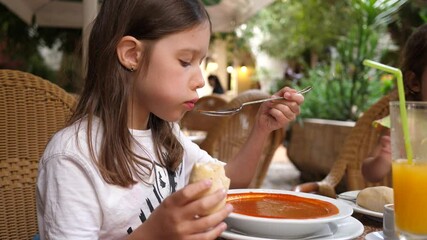 little cute girl eating tomato soup in outdoor restaurant patio in paphos cyprus