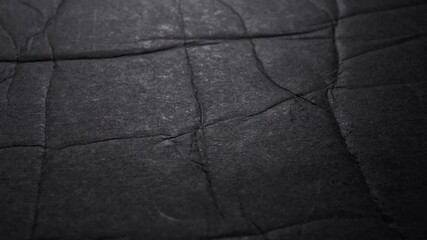 Wall Mural - Black grunge crumpled folded stained paper texture. Macro. Slow rotation. Abstract dark background