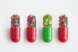 Unique green vitamin pill supplement  amongst red fruit pills, food colours concept
