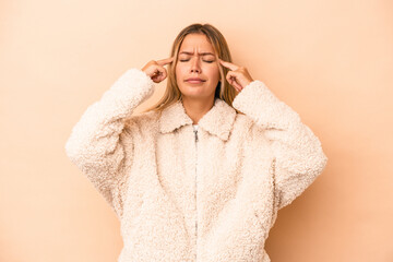 Wall Mural - Young caucasian woman isolated on beige background focused on a task, keeping forefingers pointing head.