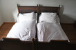 altes Doppelbett mit weißer Bettwäsche
