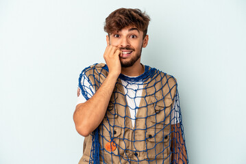 Wall Mural - Young mixed race fisherman holding a net isolated on blue background biting fingernails, nervous and very anxious.