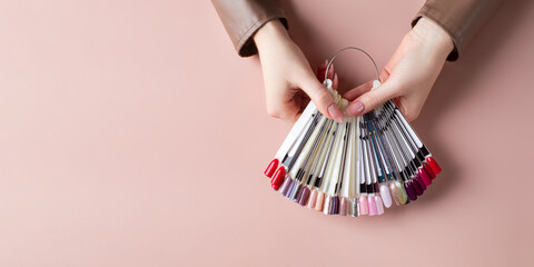 The girl holds a palette of samples of gel polishes. Top view of nail art wheel palette. Banner. Copy space.