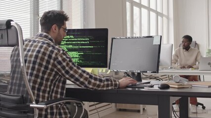 Wall Mural - stab shot of two young multi-ethnic male programmers working on computers in contemporary office. ru