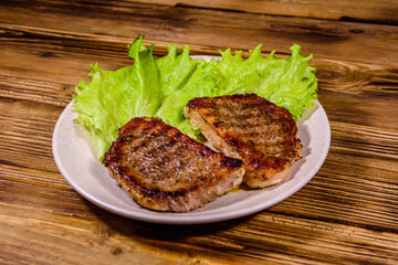 Wall Mural - Plate with roasted steaks and rosemary twigs on a wooden table